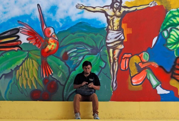 A youngster deported from the US remains sitting in front of a mural at Italian priest Ferdinando Castriotti's foundation in El Paraiso, Honduras, in the border with Nicaragua, on October 20, 2019. - Castriotti trains deportees to facilitate their social insertion. (Photo by STR / AFP)