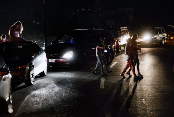 People use their mobile phones at the Distribuidor Altamira -main exit of Francisco Fajardo highway- where they can get telephone service during a partial power outage in Caracas on March 9, 2019. - Venezuela President Nicolas Maduro claimed that a new cyber attack had prevented authorities from restoring power throughout the country following a blackout on March 7 that caused chaos. The government blamed the outage on US sabotage at the central generator in Guri, in the country's south, which provides 80 percent of Venezuela with its electricity. (Photo by Matias DELACROIX / AFP)