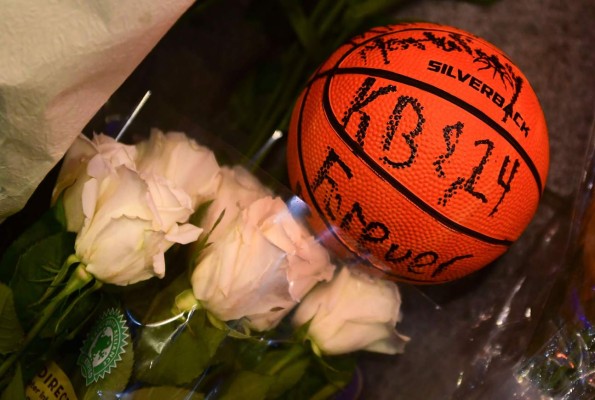 A basketball with the words 'KB & 24 Forever' written on it and white roses are placed at a makeshift memorial as fans gather to the mourn the death of NBA legend Kobe Bryant, who was killed along with his daughter and seven others in a helicopter crash on January 26, at LA Live plaza in front of Staples Center in Los Angeles on January 27, 2020. - Federal investigators sifted through the wreckage of the helicopter crash that killed basketball legend Kobe Bryant and eight other people, hoping to find clues to what caused the accident that stunned the world. (Photo by Frederic J. BROWN / AFP)