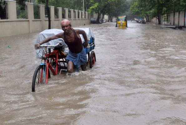 An Indian labourer pushes his cycle trishaw through floodwaters in Chennai on December 1, 2015, during a downpour of heavy rain in the southern Indian city. Heavy rains pounded several parts of the southern Indian state of Tamil Nadu and inundating most areas of Chennai, severely disrupting flights, train and bus services and forcing the postponment of half-yearly school exams. AFP PHOTO/STR