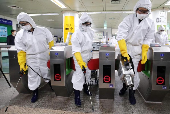 Workers wearing protective gear spray disinfectant as part of preventive measures against the spread of the COVID-19 coronavirus, at a subway station in Seoul on February 28, 2020. - K-pop megastars BTS on February 28 cancelled four concerts they were due to hold in Seoul in April, their agency said, as the coronavirus outbreak spreads in South Korea. The country has so far confirmed more than 2,000 cases of the novel coronavirus, by far the largest national total outside China, the origin of the disease. (Photo by - / YONHAP / AFP) / - South Korea OUT / REPUBLIC OF KOREA OUT NO ARCHIVES RESTRICTED TO SUBSCRIPTION USE