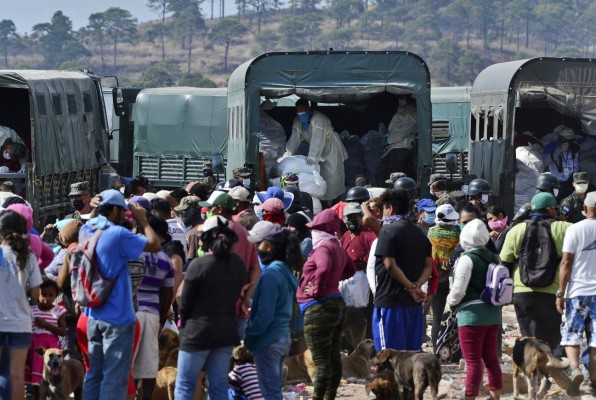 Honduran soldiers and militarized police members, wearing face masks as a preventive measure against the spread of the new coronavirus, COVID-19, distribute food at the municipal dump site in Tegucigalpa, on March 29, 2020. - The government, which declared a 'total national curfew' on March 16 in an effort to stop the virus in the country, began distributing food as part of the 'Solidary Honduras' plan that would benefit about three million people. (Photo by ORLANDO SIERRA / AFP)