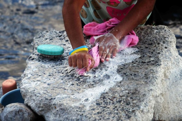 A woman washes clothes at Lempa's river polluted waters in Citala, 100 kilometres north of San Salvador on February 4, 2017. Environmental institutions and municipalities from Guatemala, Honduras and El Salvador join efforts to reduce the pollution of the Lempa river, scourged by deforestation, pollution and global warming. / AFP PHOTO / Marvin RECINOS / TO GO WITH AFP STORY BY CARLOS MARIO MARQUEZ