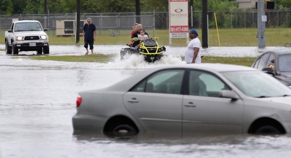 MW131. Houston (United States), 27/08/2017.- A family piled onto an ATV makes their way across the flooded roadway past pedestrians and stalled cars along Texas 249 in Houston, Texas, USA, 27 August 2017. The areas in and around Houston and south Texas are experiencing record floods after more than 24 inches of rain after Harvey made landfall in the south coast of Texas as a category 4 hurricane, the most powerful to affect the US since 2004. Harvey has weakened and been downgraded to a tropical storm and is expected to cause heavy rain for several days. (Inundaciones, Estados Unidos) EFE/EPA/MICHAEL WYKE