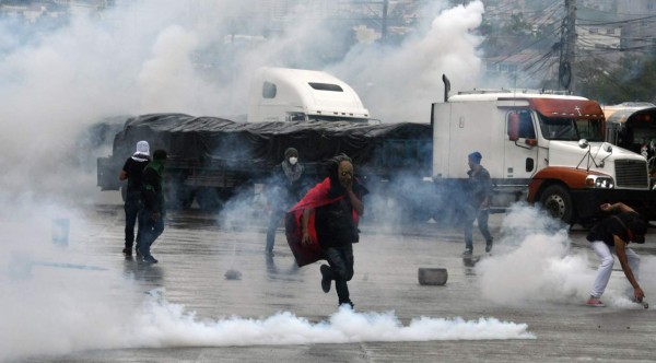 TOPSHOT - Supporters of opposition candidate Salvador Nasralla clash with Honduran Army soldiers and riot police members, during protests in Tegucigalpa, on December 18, 2017.Honduran President Juan Orlando Hernandez is declared the winner of a heavily disputed presidential election held three weeks ago, despite mounting protests and opposition claims of fraud. / AFP PHOTO / ORLANDO SIERRA