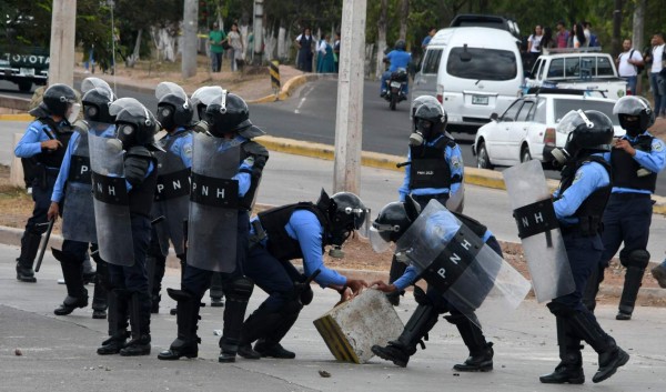 Riot police remove a roadblock on Suyapa boulevard during a crackdown on a demonstration by National Autonomous University of Honduras (UNAH) students protesting the reelection of President Juan Orlando Hernandez, in Tegucigalpa on February 5, 2018. A member of the Opposition Alliance Against the Dictatorship was shot in the head and killed in the town of Choloma, 210 km north of the Honduran capital, while taking part in a roadblock Monday. The opposition claims that at least 40 members of the Opposition Alliance Against the Dictatorship have been killed since the November 27, 2017 elections. / AFP PHOTO / ORLANDO SIERRA