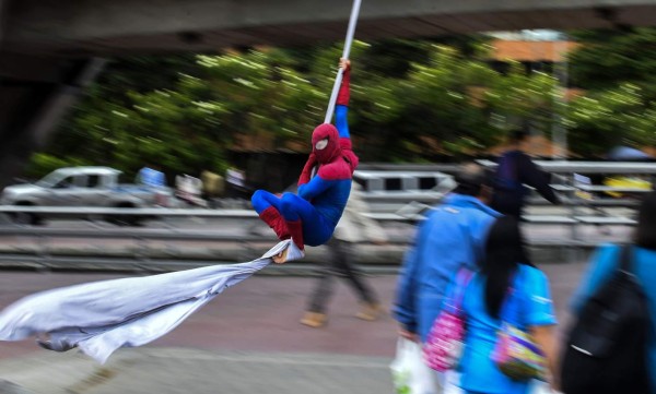 Colombian Jahn Fredy Duque, dressed as superhero 'Spiderman', performs on the streets in Bogota, Colombia on April 24, 2017. Duque hangs a white cloth 26 meters long - his 'cobweb - from a bridge near the international center of Bogota, where he performs in the street for a livelihood. / AFP PHOTO / RAUL ARBOLEDA