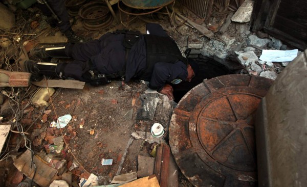 Un agente de la Policía Preventiva inspecciona una alcantarilla en busca del violador “Loco Hugo”.