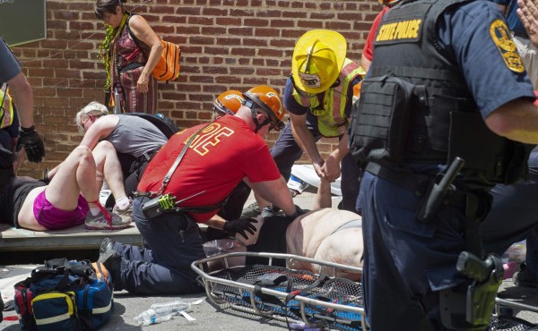 Injured people receive first-aid after a car accident ran into a crowd of protesters in Charlottesville, VA on August 12, 2017. A vehicle plowed into a crowd of people Saturday at a Virginia rally where violence erupted between white nationalist demonstrators and counter-protesters, witnesses said, causing an unclear number of injuries. / AFP PHOTO / PAUL J. RICHARDS