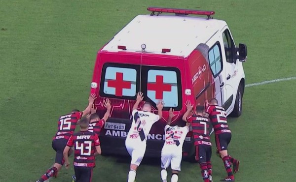 Futbolistas empujan una ambulancia averiada enmedio de la cancha