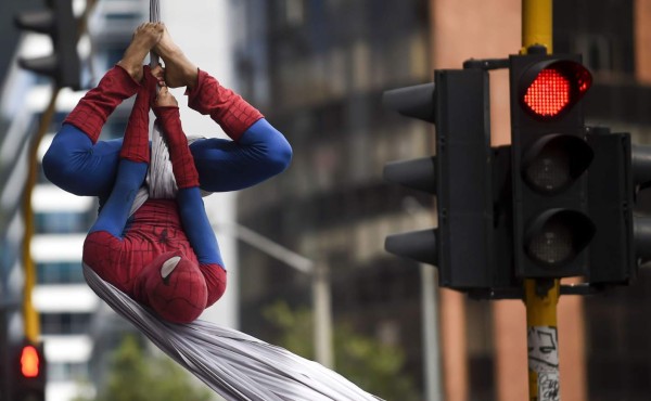 Colombian Jahn Fredy Duque, dressed as superhero 'Spiderman', performs on the streets in Bogota, Colombia on April 24, 2017. Duque hangs a white cloth 26 meters long - his 'cobweb - from a bridge near the international center of Bogota, where he performs in the street for a livelihood. / AFP PHOTO / RAUL ARBOLEDA