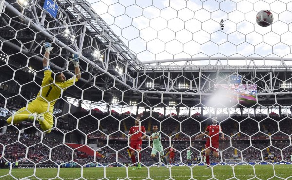 Russia's goalkeeper Igor Akinfeev (L) fails to stop the ball after Portugal's forward Cristiano Ronaldo (unseen) scored a goal during the 2017 Confederations Cup group A football match between Russia and Portugal at the Spartak Stadium in Moscow on June 21, 2017. / AFP PHOTO / Alexander NEMENOV