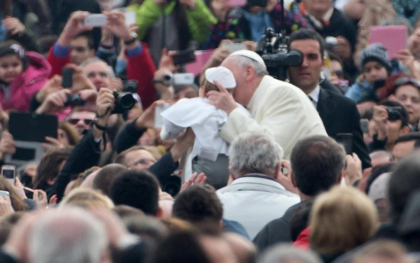 El papa Francisco besa a un niño vestido de Pontífice