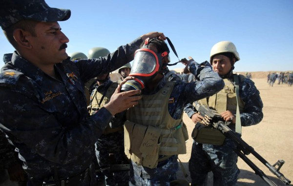 An Iraqi policeman tries on a gasmask at the Qayyarah military base, about 60 kilometres (35 miles) south of Mosul, on October 16, 2016, as they prepare for an offensive to retake Mosul, the last major population centre in the country, after regaining much of the territory the jihadists seized in 2014 and 2015. / AFP PHOTO / AHMAD AL-RUBAYE