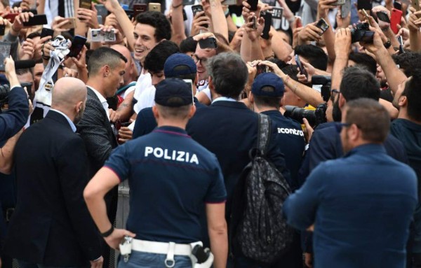 Portuguese footballer Cristiano Ronaldo signs autographs as he arrives on July 16, 2018 at the Juventus medical centre at the Alliance stadium in Turin.A Turin hit by Cristiano Ronaldo fever awaits the striker as Juventus prepare to unveil the surprise signing, that after the end of the World Cup, puts all eyes on the Italian champions and Serie A. / AFP PHOTO / Miguel MEDINA