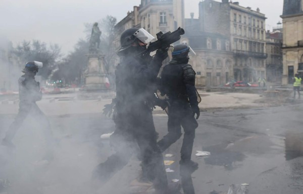 French riot police react during protests by 'Yellow vest' (gilets jaunes) anti-government demonstrators in the western French city of Bordeaux on December 29, 2018. - Police fired tear gas at 'yellow vest' demonstrators in Paris on December 29 but the turnout for round seven of the popular protests that have rocked France appeared low. The yellow vests (gilets jaunes) movement in France originally started as a protest about planned fuel hikes but has morphed into a mass protest against President's policies and top-down style of governing. (Photo by MEHDI FEDOUACH / AFP)