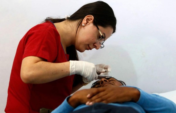 A man gets medical assistance at Italian priest Ferdinando Castriotti's foundation in El Paraiso, Honduras, in the border with Nicaragua, on October 20, 2019. - Castriotti trains deportees to facilitate their social insertion. (Photo by STR / AFP)