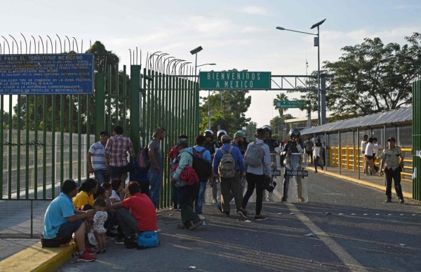 Honduran migrants wait to cross the international border bridge from Ciudad Tecun Uman in Guatemala to Ciudad Hidalgo in Mexico, on January 18, 2020. - On the eve, Mexican President Andres Manuel Lopez Obrador offered 4,000 jobs to members of the caravan in an attempt to dissuade them from traveling on to the United States. The caravan, which formed in Honduras this week, currently has around 3,000 migrants, Lopez Obrador said. (Photo by Johan ORDONEZ / AFP)