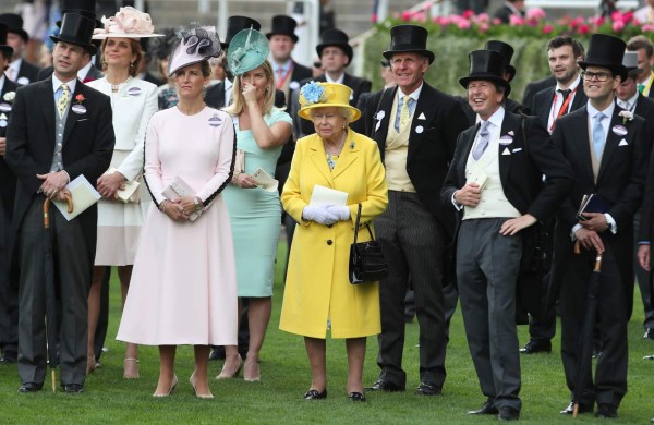 Britain's Queen Elizabeth II (C) stands with her Bloodstock and Racing Advisor, John Warren (3R) as they watch the Wolferton Rated Stakes race on day one of the Royal Ascot horse racing meet, in Ascot, west of London, on June 19, 2018. The five-day meeting is one of the highlights of the horse racing calendar. Horse racing has been held at the famous Berkshire course since 1711 and tradition is a hallmark of the meeting. Top hats and tails remain compulsory in parts of the course while a daily procession of horse-drawn carriages brings the Queen to the course. / AFP PHOTO / Daniel LEAL-OLIVAS
