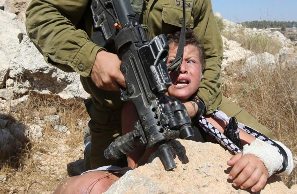 El soldado israelí toma con fuerza al niño palestino.
