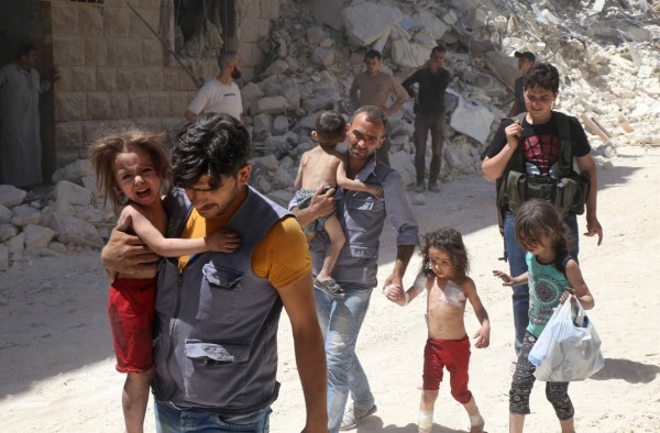 Syrian men carry injured children amid the rubble of destroyed buildings following reported air strikes on the rebel-held neighbourhood of Al-Mashhad in the northern city of Aleppo, on July 25, 2016.Air strikes and barrel bomb attacks killed 16 civilians in rebel-held parts of Aleppo province, with rebel rocket fire onto government areas killing three more, the Britain-based Syrian Observatory for Human Rights said. / AFP PHOTO / Baraa Al-Halabi