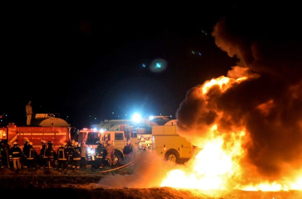 Firefighters are working at extinguishing the fire at the scene of a massive blaze trigerred by a leaky pipeline in Tlahuelilpan, Hidalgo state, on January 19, 2019. - A leaking fuel pipeline triggered a massive blaze in central Mexico, killing at least 20 people and injuring another 54, officials said. Omar Fayad, governor of Hidalgo state, said locals at the site of the leak were scrambling to steal some of the leaking oil when at least 20 of them were burned to death. (Photo by FRANCISCO VILLEDA / AFP)