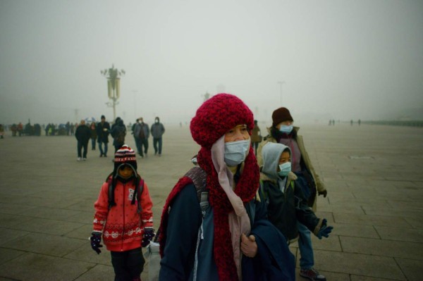 Visitors wear masks as they walk in Tiananmen Square during heavy pollution in Beijing on December 1, 2015. Beijing ordered hundreds of factories to shut and allowed children to skip school as choking smog reached over 25 times safe levels on December 1, casting a cloud over China's participation in Paris climate talks. AFP PHOTO / WANG ZHAO