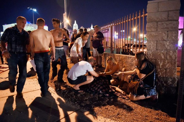LAS VEGAS, NV - OCTOBER 01: People tend to the wounded outside the festival ground after an apparent shooting on October 1, 2017 in Las Vegas, Nevada. There are reports of an active shooter around the Mandalay Bay Resort and Casino. David Becker/Getty Images/AFP== FOR NEWSPAPERS, INTERNET, TELCOS & TELEVISION USE ONLY ==