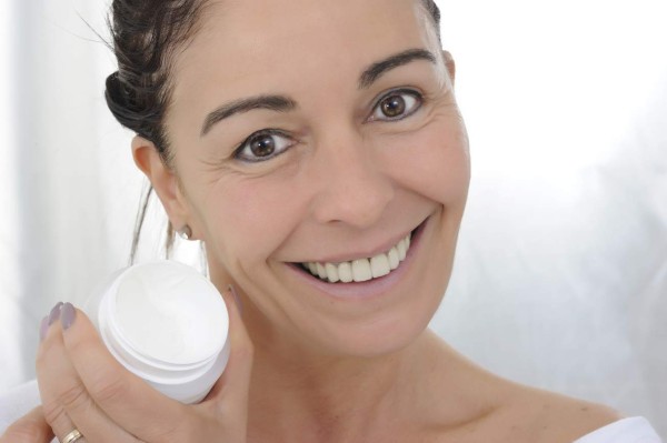 smiling 50-year-old woman with jar of face cream