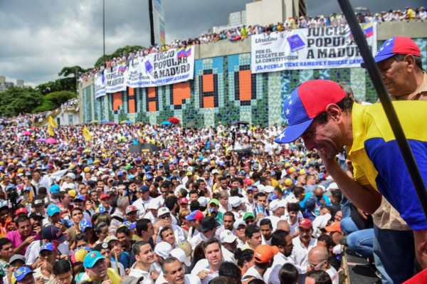 Leading opposition figure Henrique Capriles listens to supporters during a rally against the government of Venezuelan President Nicolas Maduro in Caracas on October 26, 2016. Opponents of Maduro rallied in the streets as the leftist leader convened a crisis security meeting resisting their efforts to drive him from power. Thousands of opposition supporters began to gather at seven points around Caracas in the morning planning to march and join up in the east of the capital. / AFP PHOTO / Ronaldo SCHEMIDT