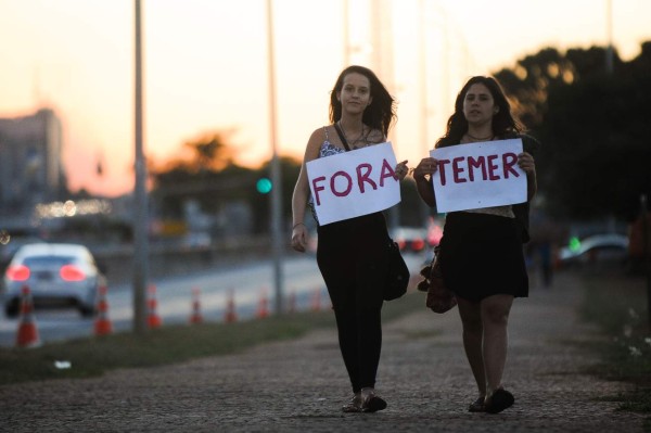 Women hold signs reading 'Temer out', as they demonstrate against Brazilian acting President Michel Temer in Brasilia, August 26, 2016. Angry exchanges erupted at suspended Brazilian president Dilma Rousseff's impeachment trial Friday, while her key ally, Luiz Lula Inacio da Silva, faced corruption charges on a day of turmoil for Latin America's biggest country. / AFP PHOTO / ANDRESSA ANHOLETE