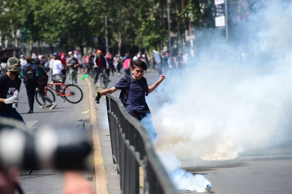 Demonstrators clash with riot police during protests in Santiago, on October 20, 2019. - Fresh clashes broke out in Chile's capital Santiago on Sunday after two people died when a supermarket was torched overnight as violent protests sparked by anger over economic conditions and social inequality raged into a third day. (Photo by Martin BERNETTI / AFP)
