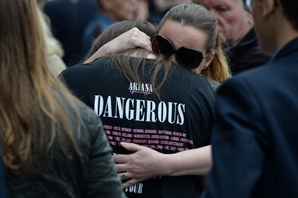 TOPSHOT - A woman (R) hugs a girl, wearing a t-shirt from Ariana Grande's Dangerous Woman near floral tributes in Albert Square in Manchester, northwest England on May 24, 2017, following the May 22 terror attack at the Manchester Arena.Police on Tuesday named Salman Abedi -- reportedly British-born of Libyan descent -- as the suspect behind a suicide bombing that ripped into young fans at an Ariana Grande concert at the Manchester Arena on May 22, as the Islamic State group claimed responsibility for the carnage. / AFP PHOTO / CHRIS J RATCLIFFE
