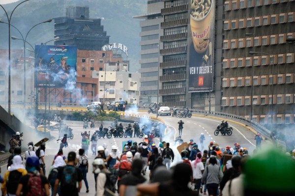 Venezuelan opposition activists clash with the security forces during a protest march on the freeway against the government of Nicolas Maduro in Caracas on May 13, 2017.Daily clashes between demonstrators -who blame elected President Nicolas Maduro for an economic crisis that has caused food shortages- and security forces have left 38 people dead since April 1. Protesters demand early elections, accusing Maduro of repressing protesters and trying to install a dictatorship. / AFP PHOTO / FEDERICO PARRA