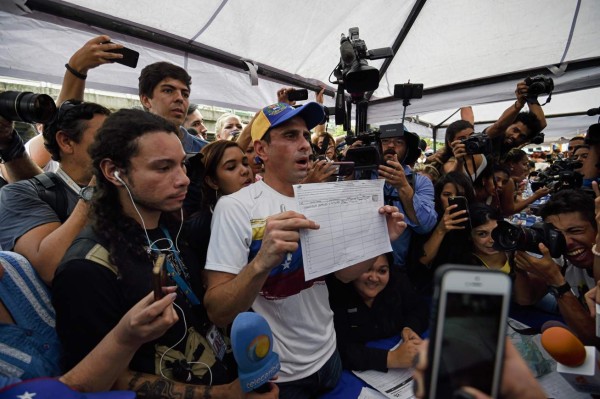 Venezuelan opposition leader and Miranda State governor Henrique Capriles signs the form to activate the referendum on cutting President Nicolas Maduro's term short, in Caracas on April 27, 2016.Opponents of Venezuelan President Nicolas Maduro hope to hold a referendum on removing him from office as early as November, a leading opposition figure said Wednesday. The center-right opposition has started gathering signatures to launch the first step towards a referendum to get rid of the socialist leader, whom they blame for an economic crisis and rising unrest. / AFP PHOTO / JUAN BARRETO