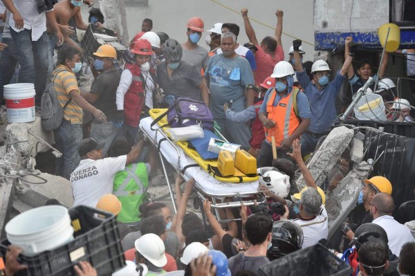 Rescuers, firefighters, policemen, soldiers and volunteers remove rubble and debris from a flattened building in search of survivors after a powerful quake in Mexico City on September 19, 2017.A devastating quake in Mexico on Tuesday killed more than 100 people, according to official tallies, with a preliminary 30 deaths recorded in the capital where rescue efforts were still going on. / AFP PHOTO / YURI CORTEZ
