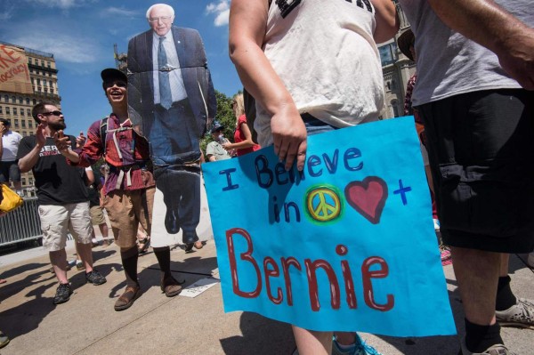 A supporter of former US Democratic presidential candidate Bernie Sanders holds a cardboard cutout of Sanders in Philadelphia on July 24, 2016, one day before the Democrats gather to formally annoint Hillary Clinton as their candidate for the November presidential election at the Democratic National Convention. / AFP PHOTO / NICHOLAS KAMM
