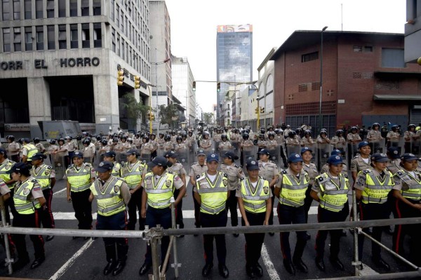 Riot police clash with opposition demonstrators during a protest against the government of President Nicolas Maduro on the anniversary of the 1958 uprising that overthrew the military dictatorship, in Caracas on January 23, 2019. - Venezuela's National Assembly head Juan Guaido declared himself the country's 'acting president' on Wednesday during a mass opposition rally against leader Nicolas Maduro. (Photo by YURI CORTEZ / AFP)