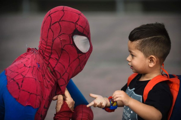 Colombian Jahn Fredy Duque, dressed as superhero 'Spiderman', talks to a little boy while performing on the streets in Bogota, Colombia on April 24, 2017. Duque hangs a white cloth 26 meters long - his 'cobweb - from a bridge near the international center of Bogota, where he performs in the street for a livelihood. / AFP PHOTO / RAUL ARBOLEDA