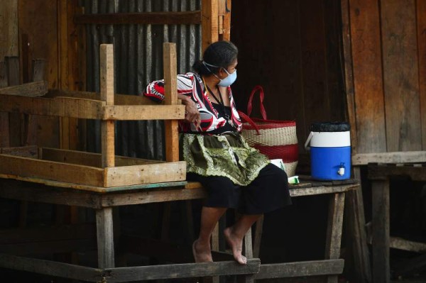 A woman wearing a face mask sits outside a market amid the 'absolute curfew' ordered by the Honduran government to slow the spread of the new coronavirus, COVID-19 in Tegucigalpa on April 4, 2020. - The number of people infected with COVID-19 reached 264 and 15 deaths, in the Central American country. (Photo by ORLANDO SIERRA / AFP)