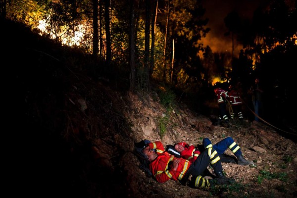 TOPSHOT - Firefighters rest during a wildfire at Penela, Coimbra, central Portugal, on June 18, 2017. A wildfire in central Portugal killed at least 25 people and injured 16 others, most of them burning to death in their cars, the government said on June 18, 2017. Several hundred firefighters and 160 vehicles were dispatched late on June 17 to tackle the blaze, which broke out in the afternoon in the municipality of Pedrogao Grande before spreading fast across several fronts. / AFP PHOTO / PATRICIA DE MELO MOREIRA