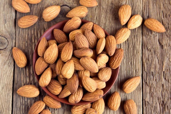 Almonds over rustic wooden background, healthy vegetarian snack