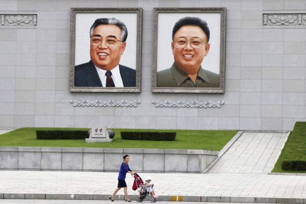 GRA137. PYONGYANG, 02/08/2017.- Un mujer con un carrito de niños pasa delante de los retratos de los líderes Kim il sung y Kim Jong il en la plaza Kim il Sung de Pyongyang. EFE/Ramón Abarca