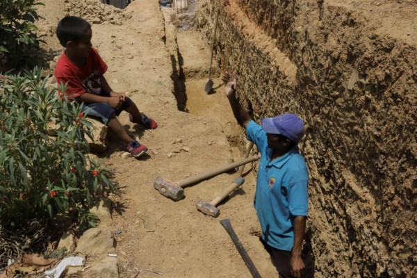 TEG1001. TEGUCIGALPA (HONDURAS), 09/05/2019.- Un hombre trabaja haciendo una zanja mientras su hijo lo observa este jueves en Tegucigalpa (Honduras). Honduras ha mantenido su estabilidad macroeconómica en los últimos años, pero no ha conseguido mejorar la inclusividad del crecimiento, por lo que la pobreza continúa afectando al 60 % de los hondureños, alertó este jueves en un libro el Banco Interamericano de Desarrollo (BID).EFE/Gustavo Amador