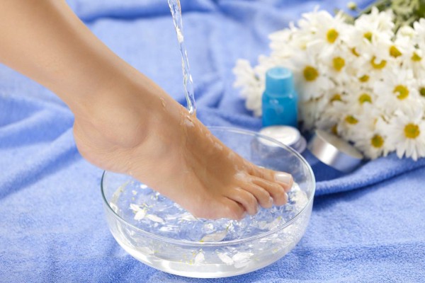 Foot bath; water being poured on woman foot during spa treatment