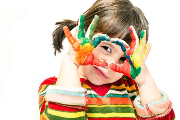 Four years old girl looking through painted hands.