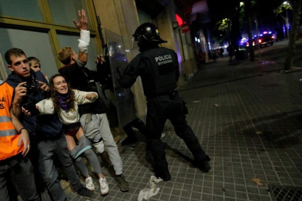 Protesters clash with a policeman in Barcelona, on October 18, 2019, after violence escalated during clashes, with radical separatists hurling projectiles at police, who responded with teargas and rubber bullets sparking scenes of chaos in the city centre. - The deterioration came after several hours of clashes on the fifth consecutive day of protests in the Catalan capital and elsewhere over Spain's move to convict nine separatist leaders of sedition over a failed independence bid two years ago. (Photo by Pau Barrena / AFP)