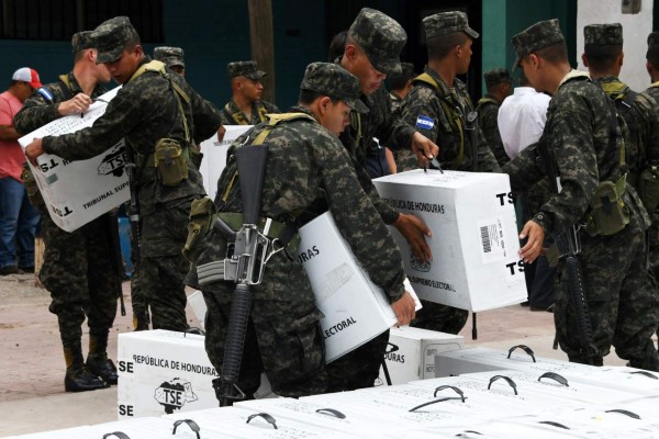 Honduran army soldiers carry election material to polling stations in Tegucigalpa on November 25, 2017, the day before the general elections. President Juan Orlando Hernandez is poll favorite for Sunday's elections, and expects to be re-elected despite the one-term limit set by the constitution. His conservative National Party contends that a 2015 Supreme Court ruling voided that restriction. But the opposition argues that the court does not have the power to overrule the constitution. / AFP PHOTO / Orlando SIERRA