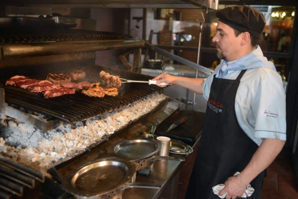 A cooker grills meat at a traditional grill restaurant in Buenos Aires, on October 27, 2015. Sausages, ham and other processed meats cause bowel cancer, and red meat 'probably' does too, a UN agency warned Monday, in a potentially heavy blow for the fast-growing livestock industry.A review of 800 studies from around the world found 'sufficient evidence in humans that the consumption of processed meat causes colorectal cancer,' said the International Agency for Research on Cancer (IARC). AFP PHOTO / EITAN ABRAMOVICH