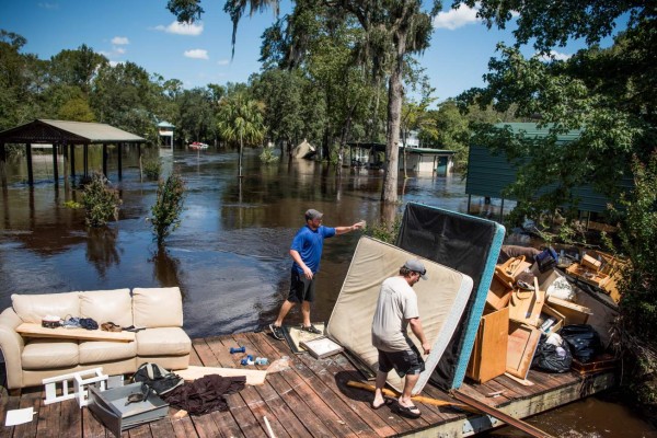 MIDDLEBURG, FL - SEPTEMBER 13: Marc St. Peter, left, and Chris Wisor lend a hand cleaning up as floodwaters from Hurricane Irma recede September 13, 2017 in Middleburg, Florida. Flooding in town from the Black Creek topped the previous high water mark by about seven feet and water entered the second story of many homes. Sean Rayford/Getty Images/AFP